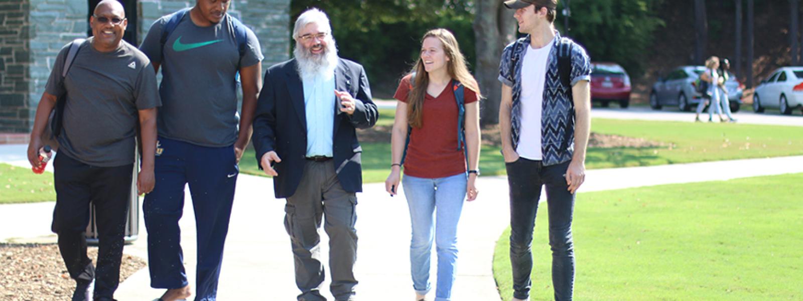 Dr. John Crutchfield walks across the CIU campus with students. 