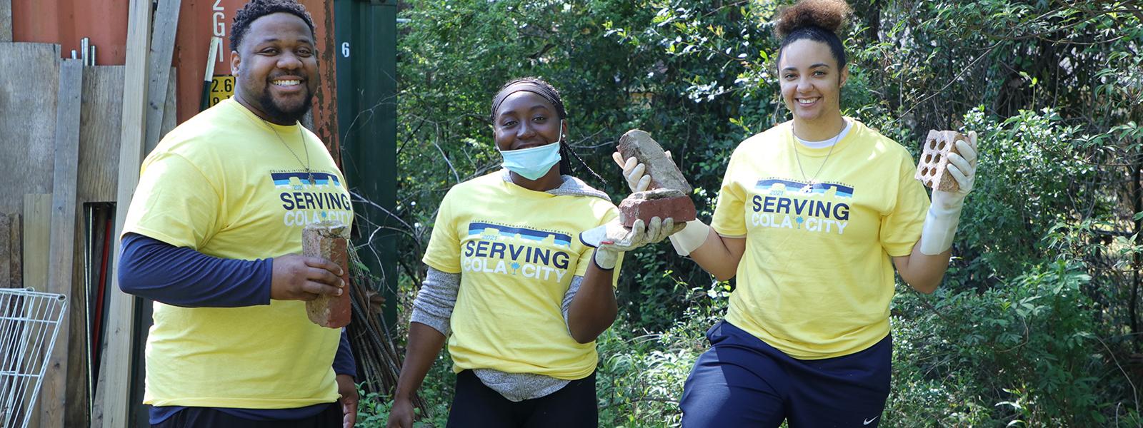 Women's Head Basketball Coach Danielle Fleming (right), Assistant Coach Daron Fleming and student Britney Brown assist in clean up during a service day in 2021. 