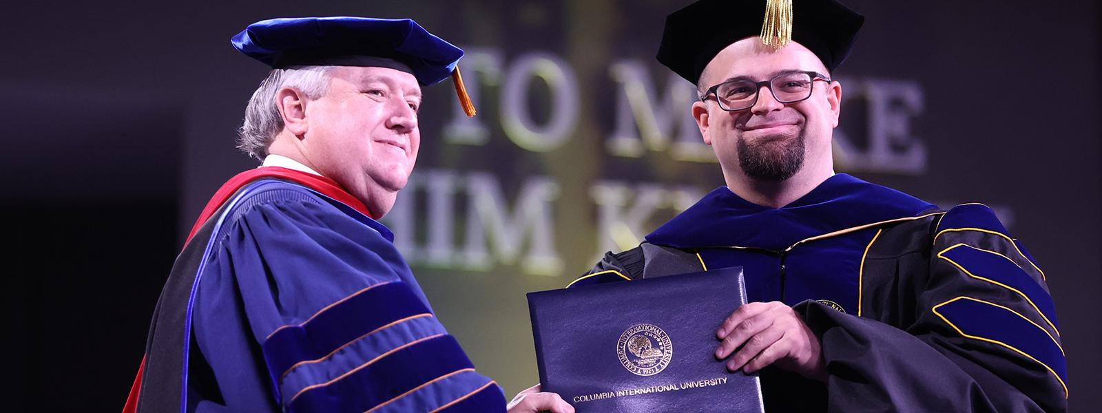 Dr. Josh Waltman (right) receives his Ph.D. in Theological Studies from President Dr. Mark A. Smith 