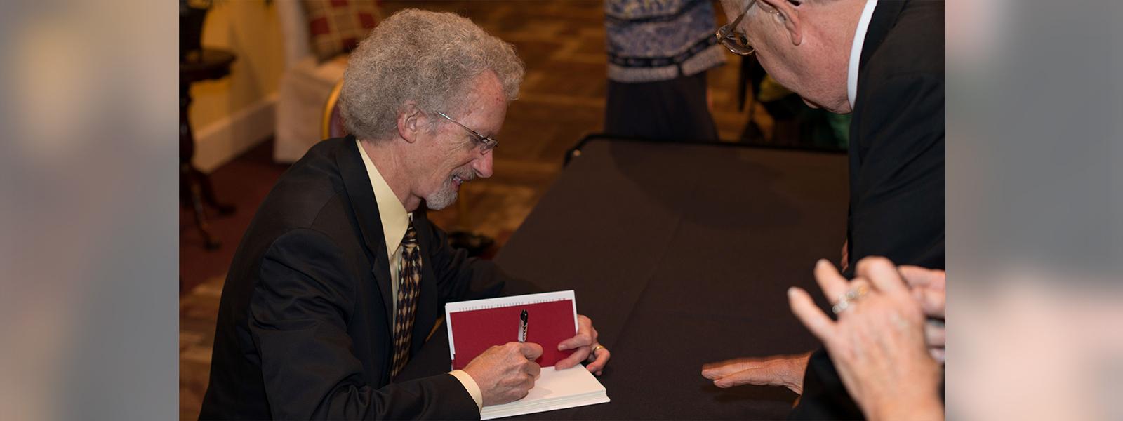 Phillip Yancey signs one of his books at the 90th anniversary celebration of CIU.