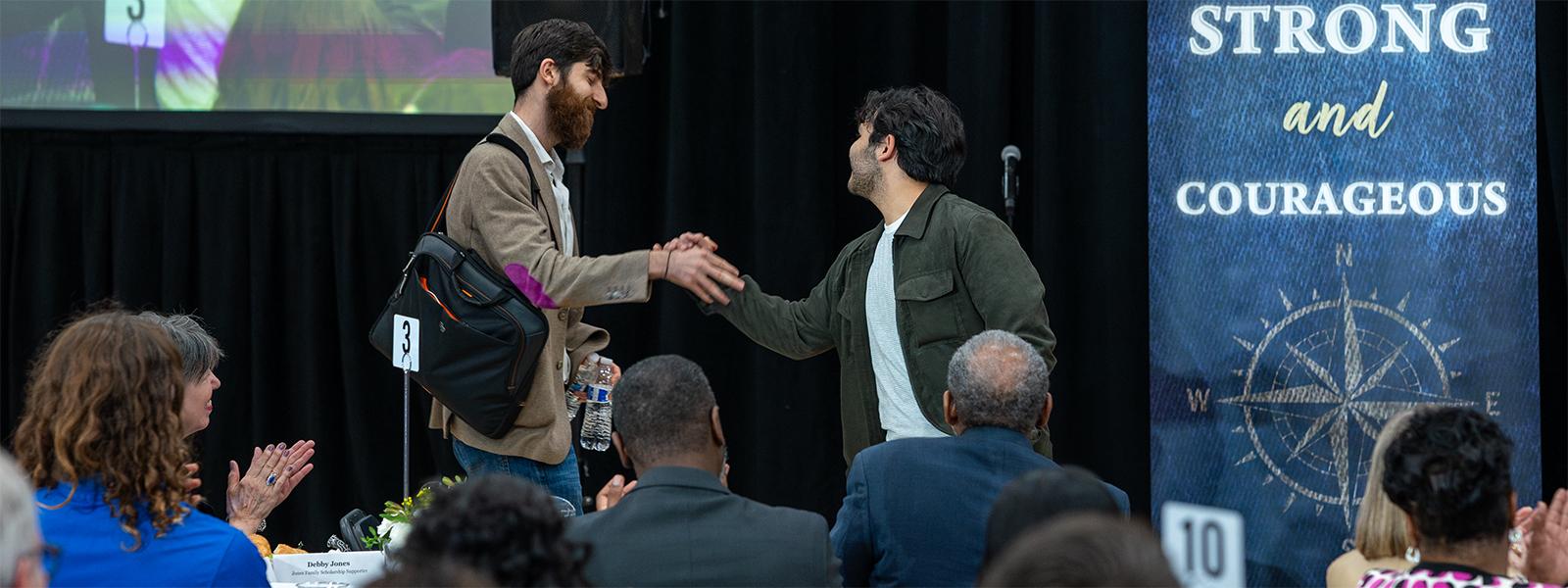 Gvidon Stamboltsyan, a student from Armenia, (left) greets "M," a student from Azerbaijan on the platform at the Partner Appreciation Lunch. (Photo by Noah Allard)
