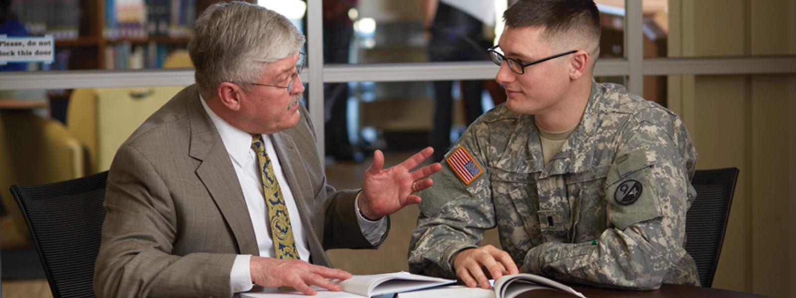 A seminary professor speaking with a military chaplaincy student in an office environment.