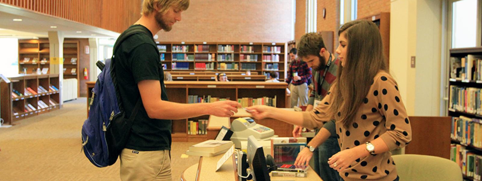 A photo of a student worker assisting a student in the library at Columbia International University.