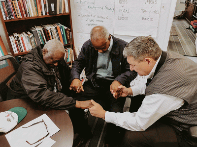 Executive Director and CIU alumnus Rob Settle (right), prays with board member Henry Hennagan (left) and volunteer David Coleman at Providence Home. (Photo provided) 