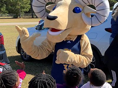 Forest Heights Elementary kindergarten students reach high to "high-five" Ramey, the CIU mascot. (Photo by Bob Holmes)