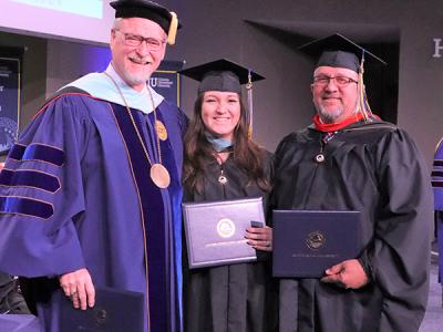 Father and daughter graduates Robert Hall and Krystil Burke pose with Interim President Dr. Rick Christman. 