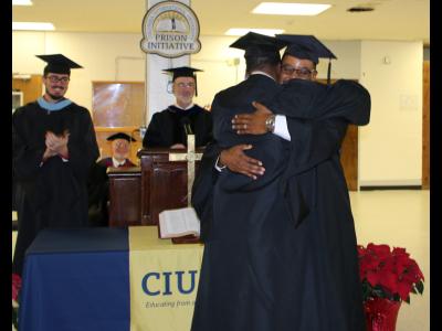 A graduate of the CIU Prison Initiative receives his diploma and hugs Initiative Director Andre Melvin. 